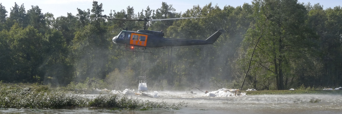 Ein Hubschrauber lädt einen Sandsack während des Hochwassers 2010 an der Schwarzen Elster ab.