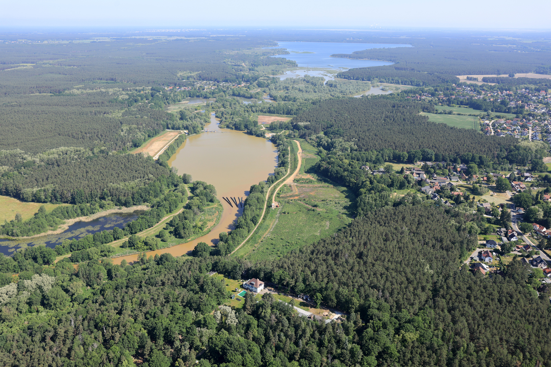 Die Vorsperre Bühlow dient heute der Reduzierung der Eisenockerfracht in der Spree Luftaufnahme, überwiegend mit Nadelwald. In der Bildmitte sieht man ein Rückhaltebecken mit bräunlichem Wasser, genannt Vorsperre Bühlow. Sie dient heute zur Reduzierung der Eisenockerfracht in der Spree. Im Hintergrund zu sehen ist die Talsperre Spremberg mit blauem Wasser. Rechts im Wald befindet sich die Ortschaft Bühlow.